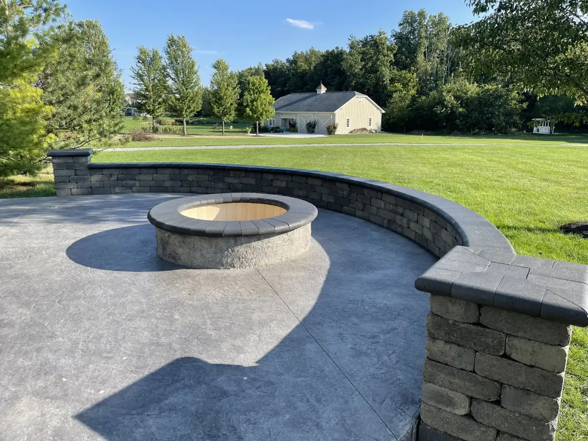 Custom fire pit with surrounding paver patio and seating wall at a Central Ohio home