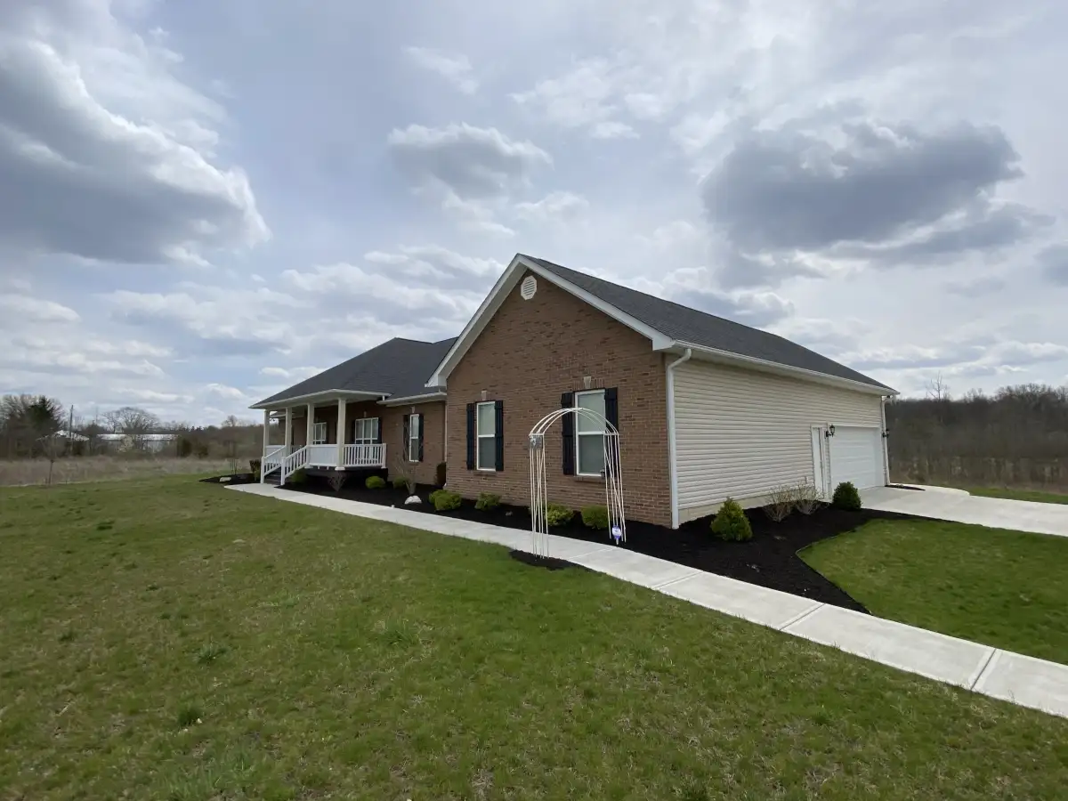 Backyard landscape installation with trees, shrubs, and decorative stone border